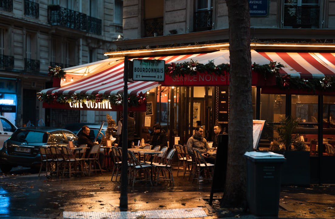 A Group Of People Sitting At A Table Outside Of A Restaurant