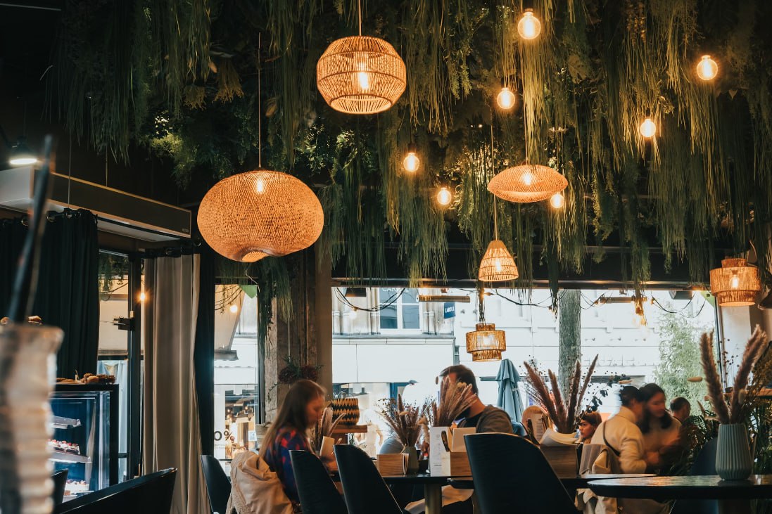 A Group Of People Sitting At Tables Under Lanterns