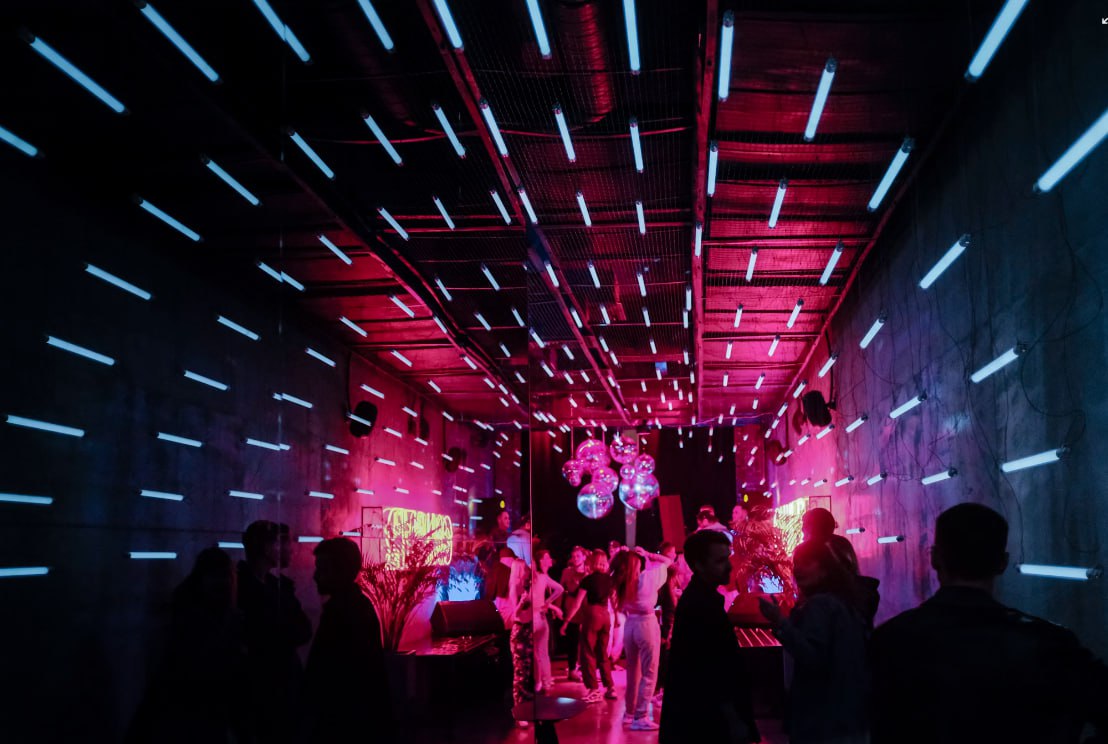 A Group Of People Standing Around In A Room