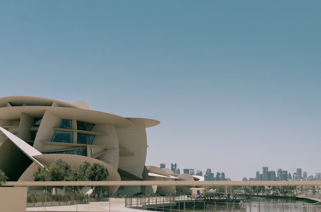 A Large Building With A Curved Roof Next To A Body Of Water