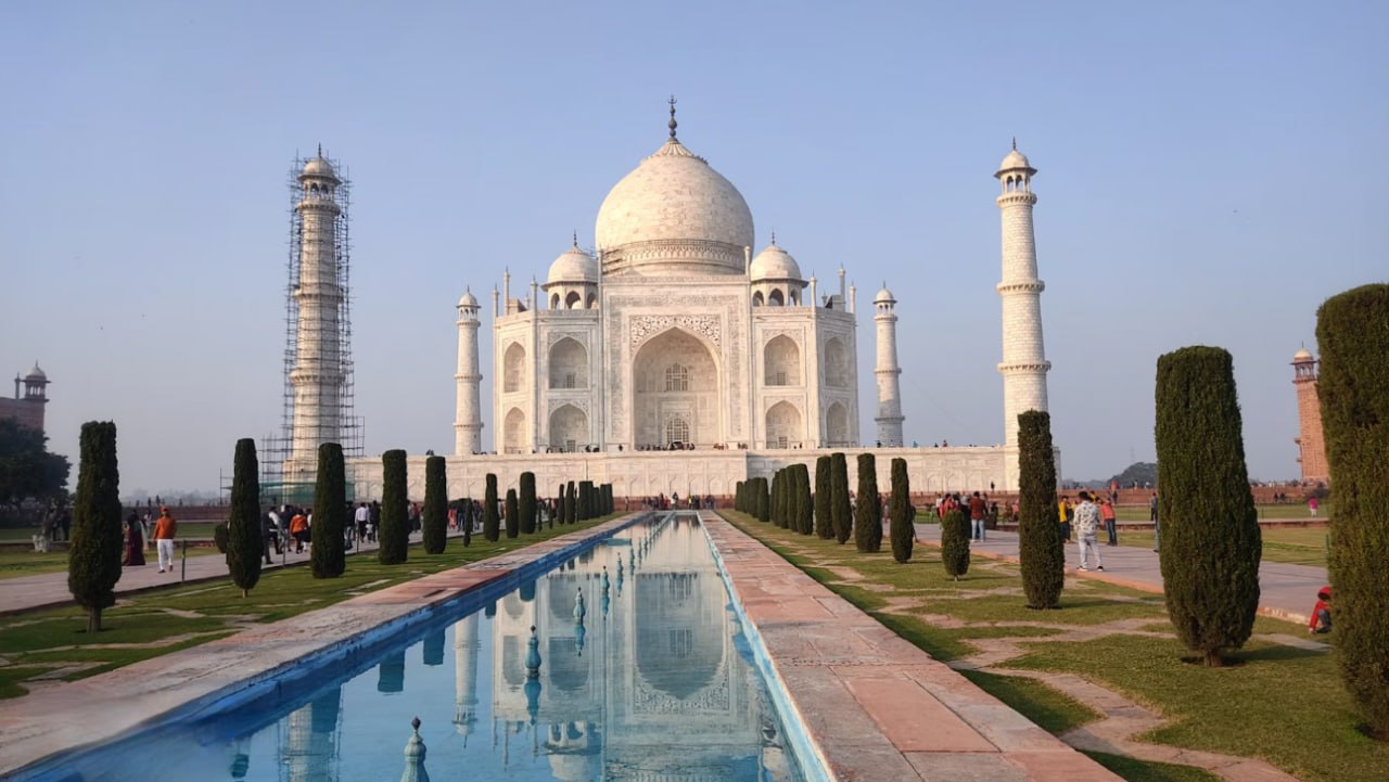 A Large White Building With A Long Pool In Front