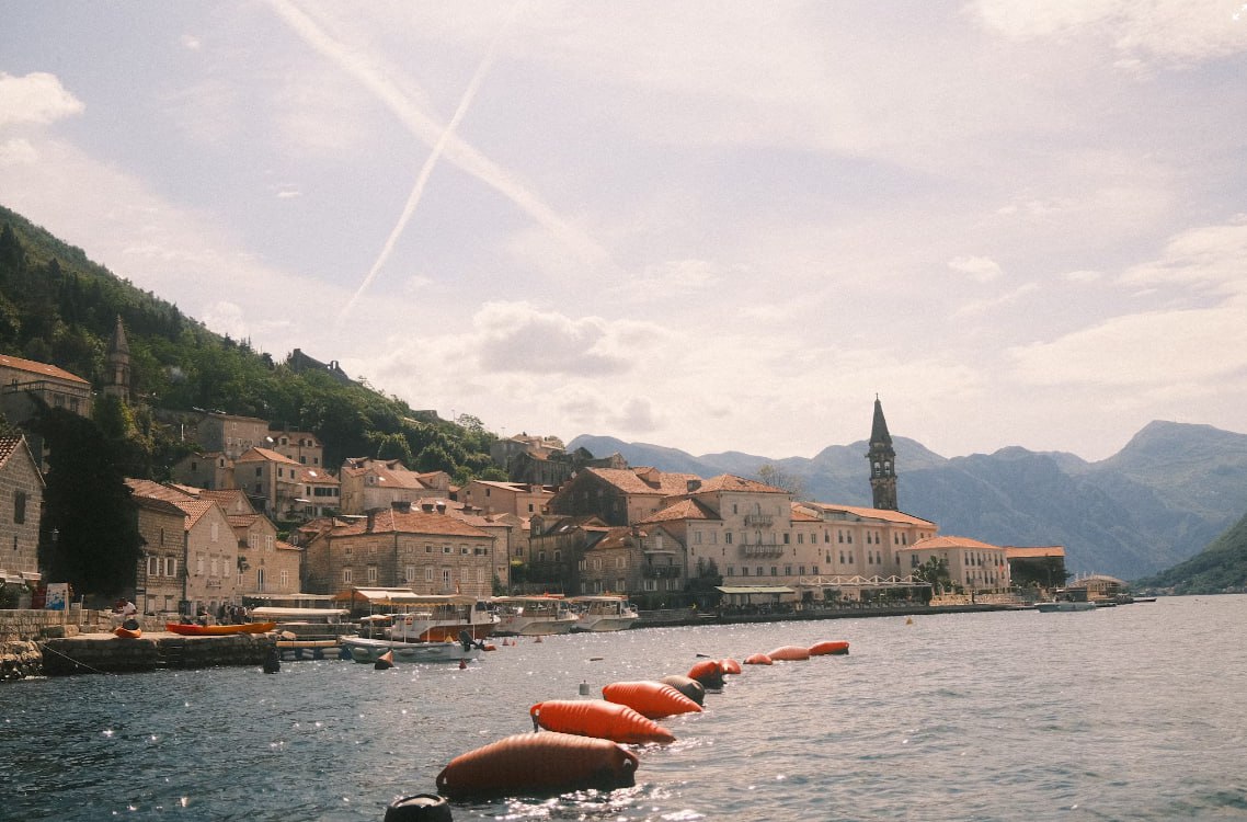 A Row Of Orange Buoys Sitting On The Side Of A Body Of Water