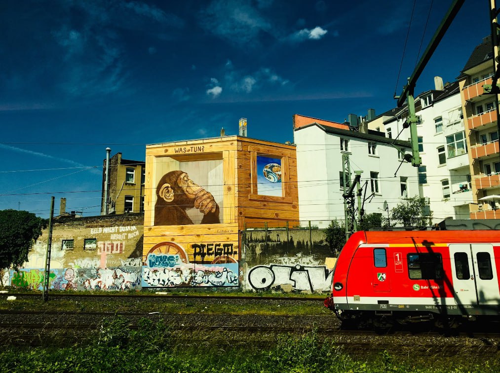 A Train Traveling Past A Tall Building With Graffiti