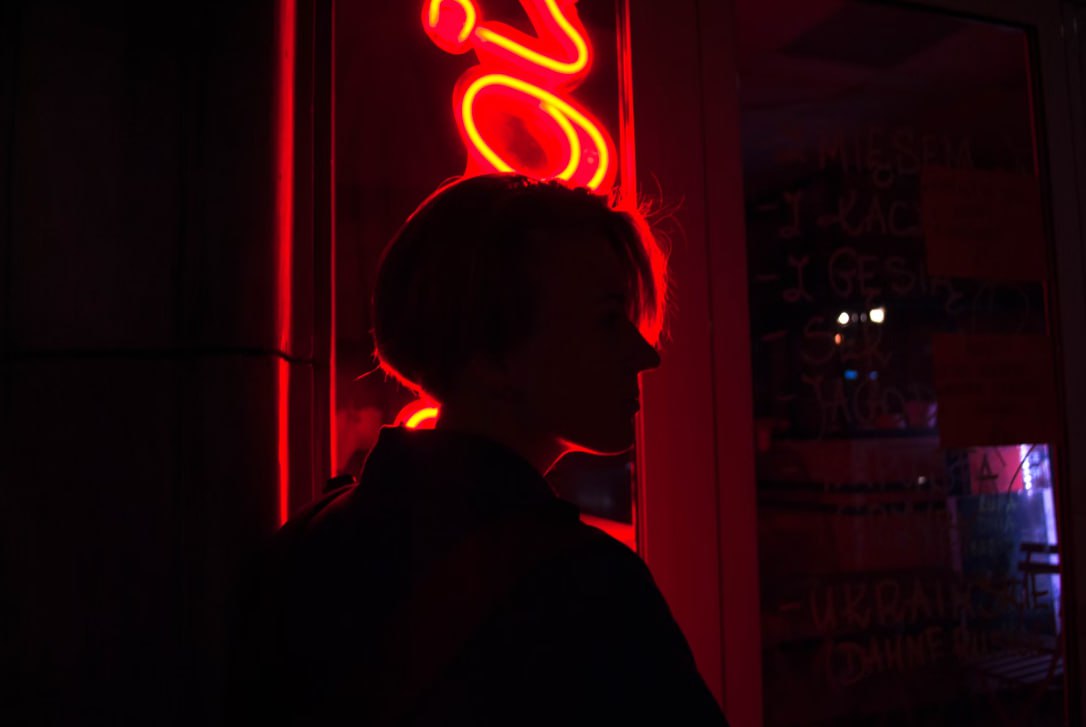 A Woman Standing In Front Of A Neon Sign