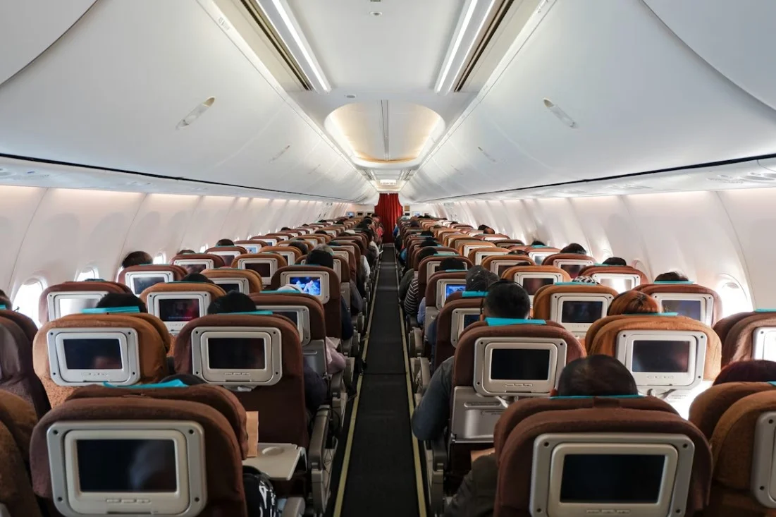 Cabina de avión con asientos de pasajeros y compartimentos superiores para equipaje