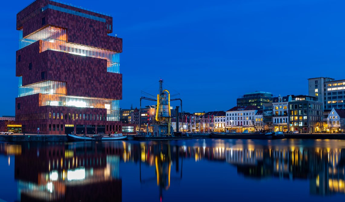 Brown Concrete Building Near Body Of Water During Night Time