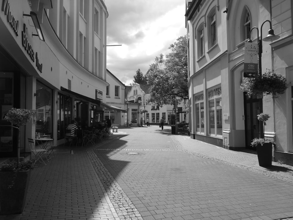 Grayscale Photo Of People Walking On Sidewalk Near Buildings