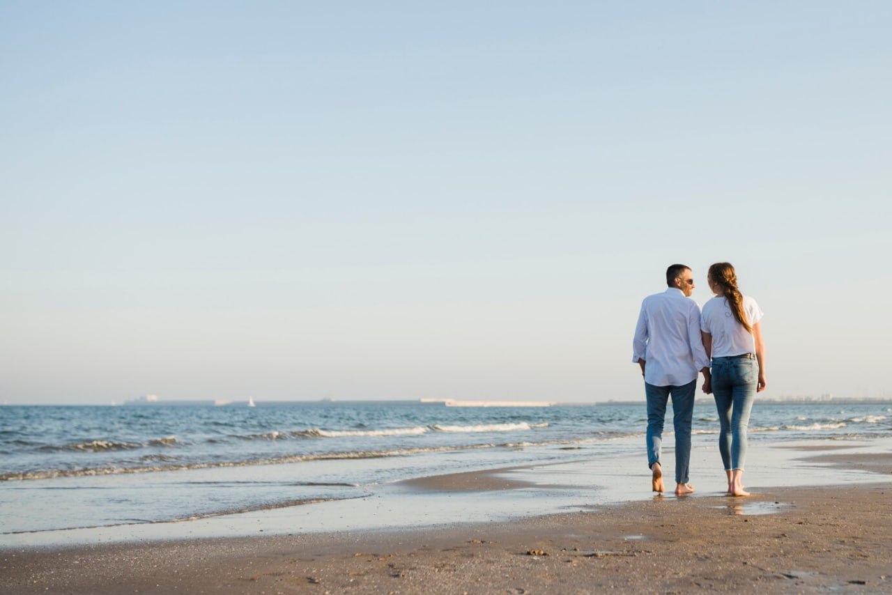 rear_view_of_couple_walking_on_sandy_beach