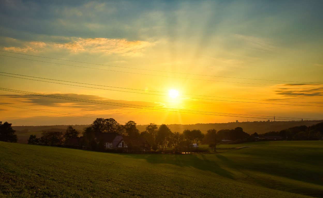The Sun Is Setting Over A Green Field