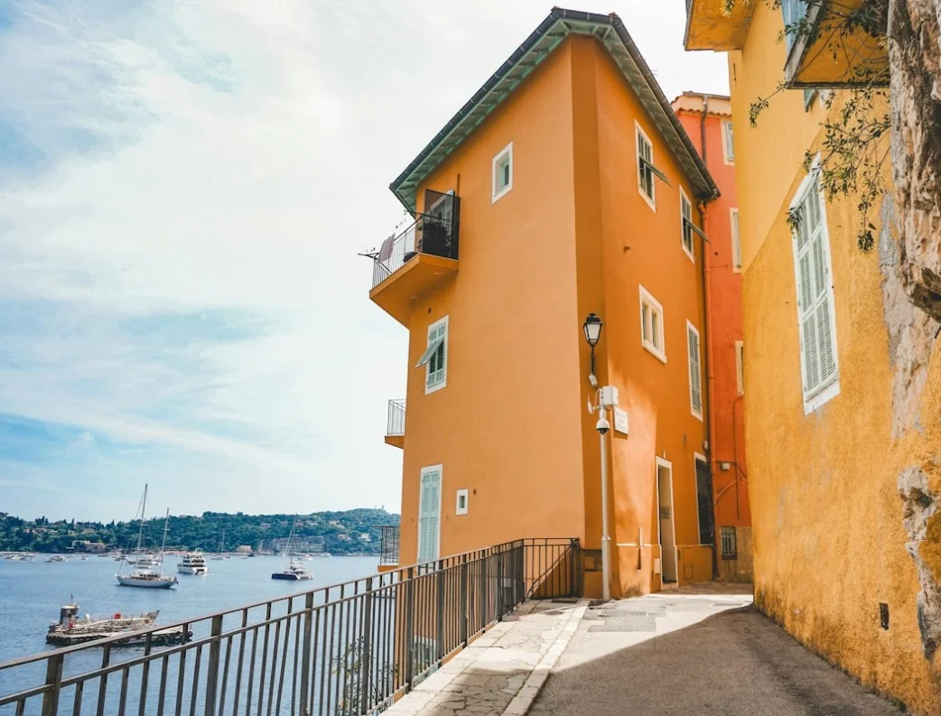 villefranche-sur-Mer-a-yellow-building-on-the-side-of-a-road-next-to-a-body-of-water