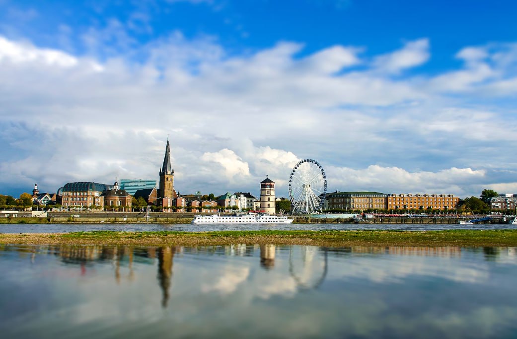 White Ferris Wheel Near Body Of Water Under Blue Sky During Daytime