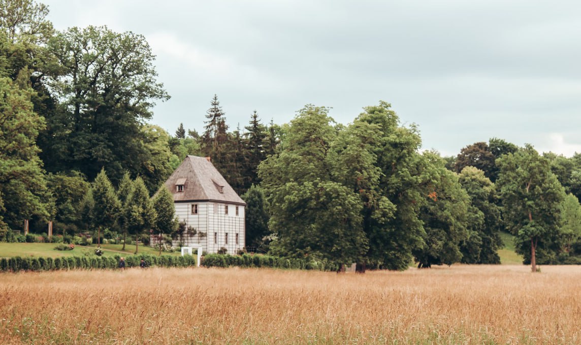 White Wooden House In The Middle Of Brown Grass Field